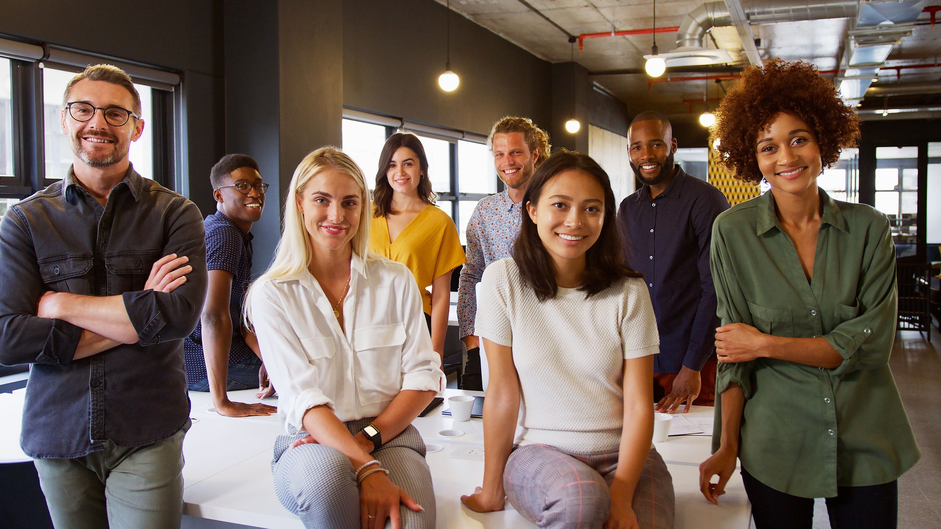 Portrait Of Smiling Multi-Cultural Business Team In Modern Open Plan Office Together