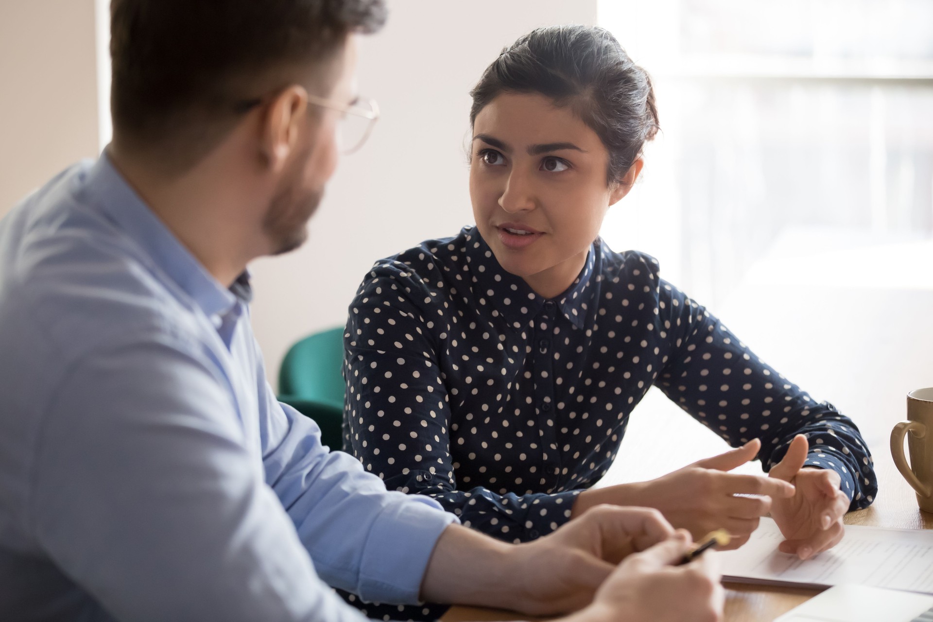 Indian female mentor worker talking to male coworker in office